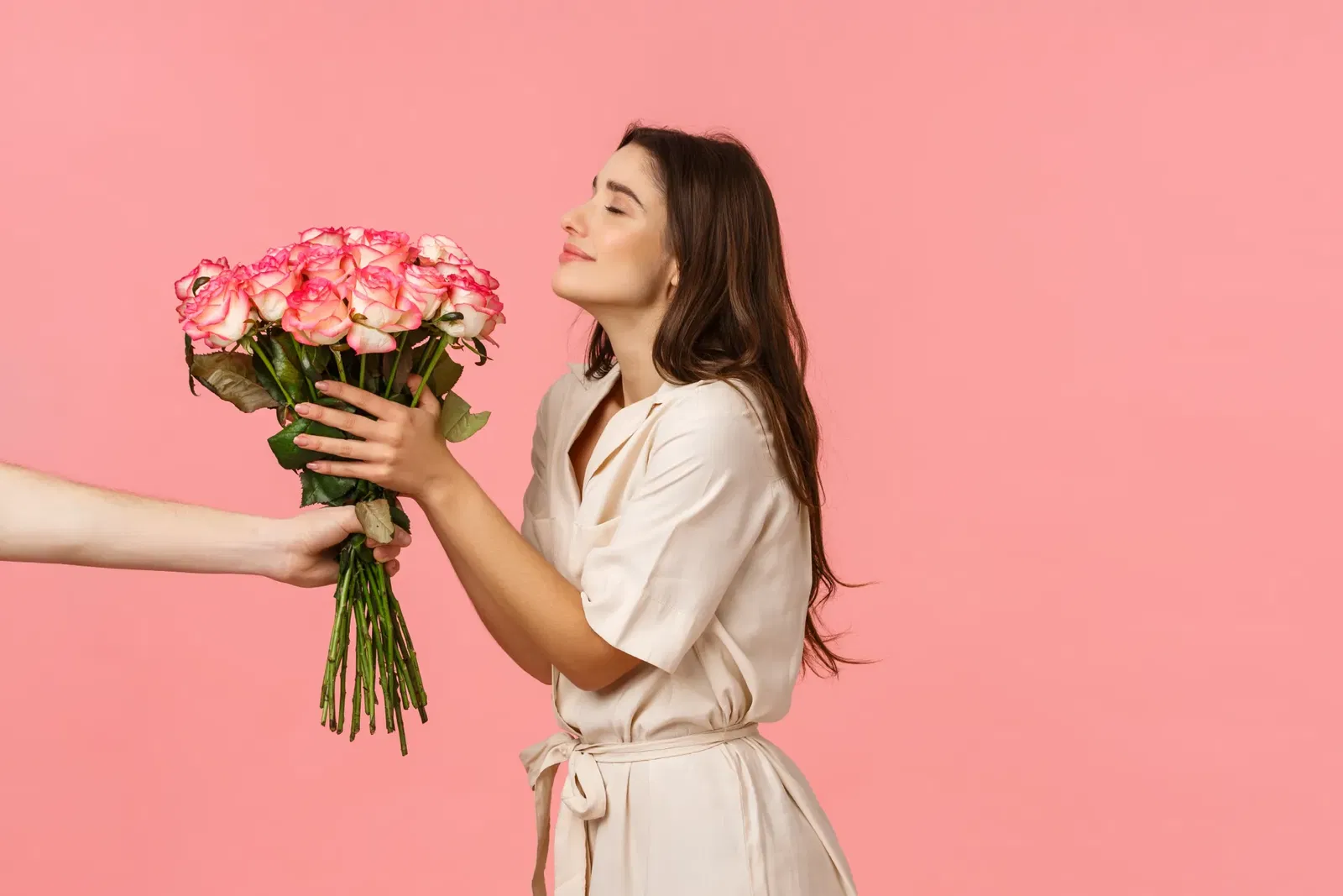 Sommerlich gekleidete Frau nimmt freudig ein Bund rosa Rosen entgegen. Sommerlich gekleidete Frau nimmt freudig ein Bund rosa Rosen entgegen.