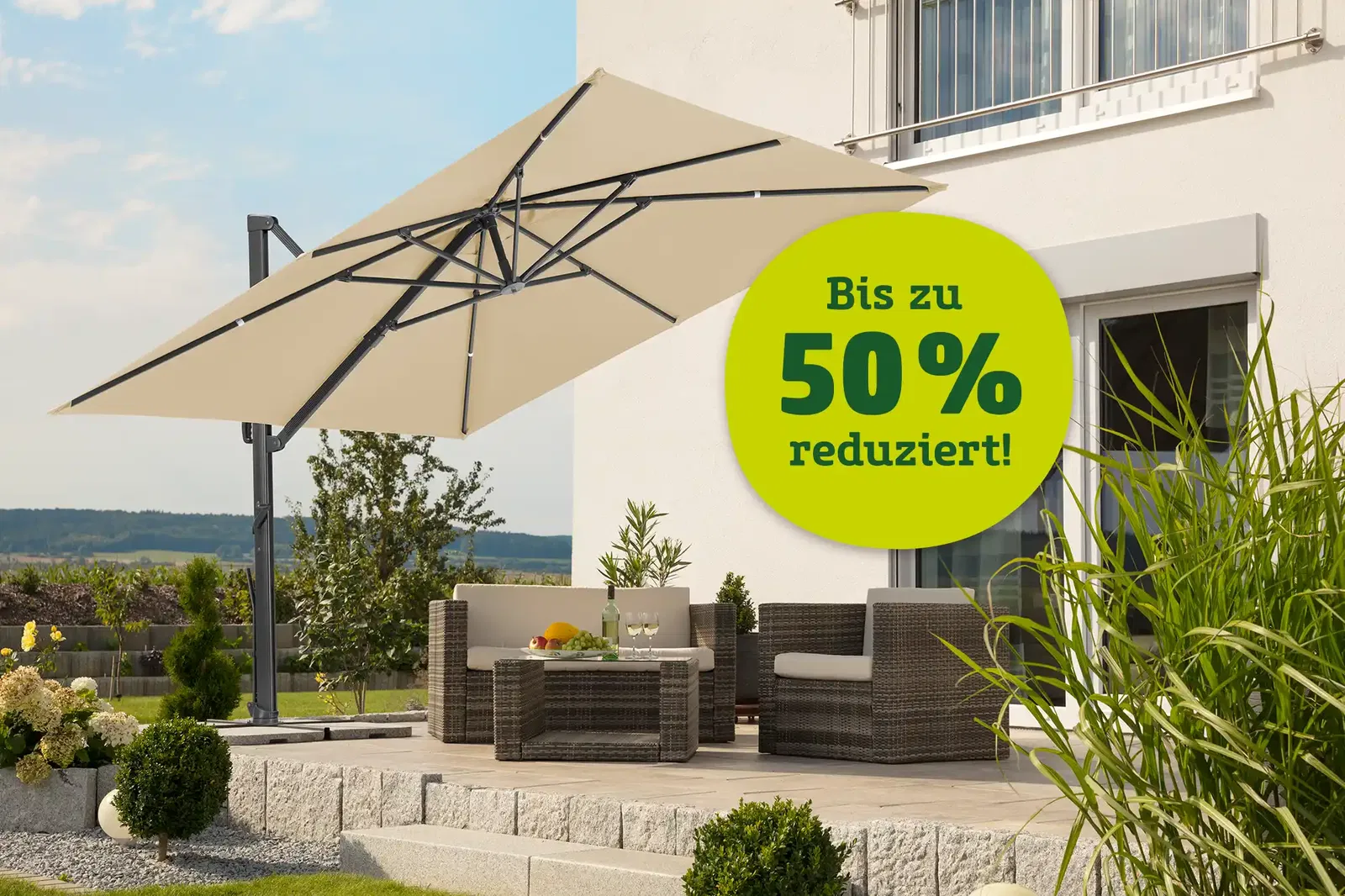 Sonnenschirm und Gartenmöbel auf einer idyllischen Terrasse. Hinweis: Bis zu 50 % reduziert.