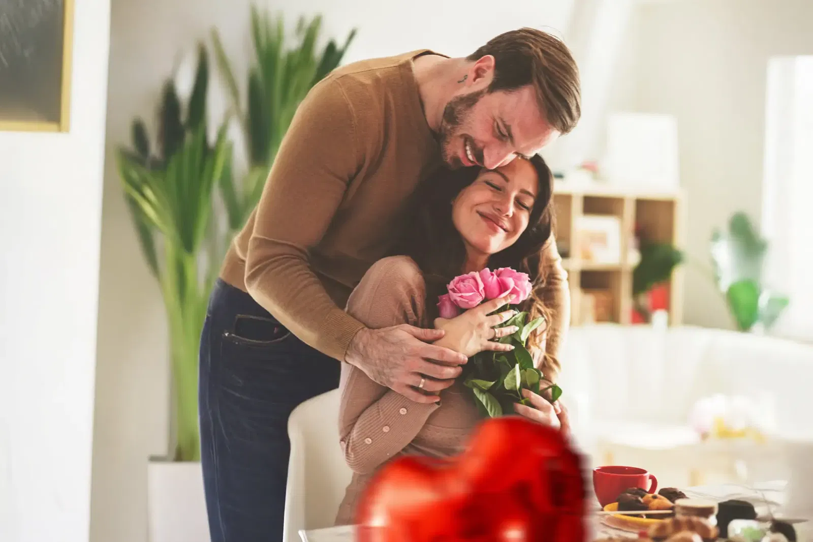 Glückliches Pärchen. Mann übergibt seiner Frau rosa Rosen zum Valentinstag. Glückliches Pärchen. Mann übergibt seiner Frau rosa Rosen zum Valentinstag.
