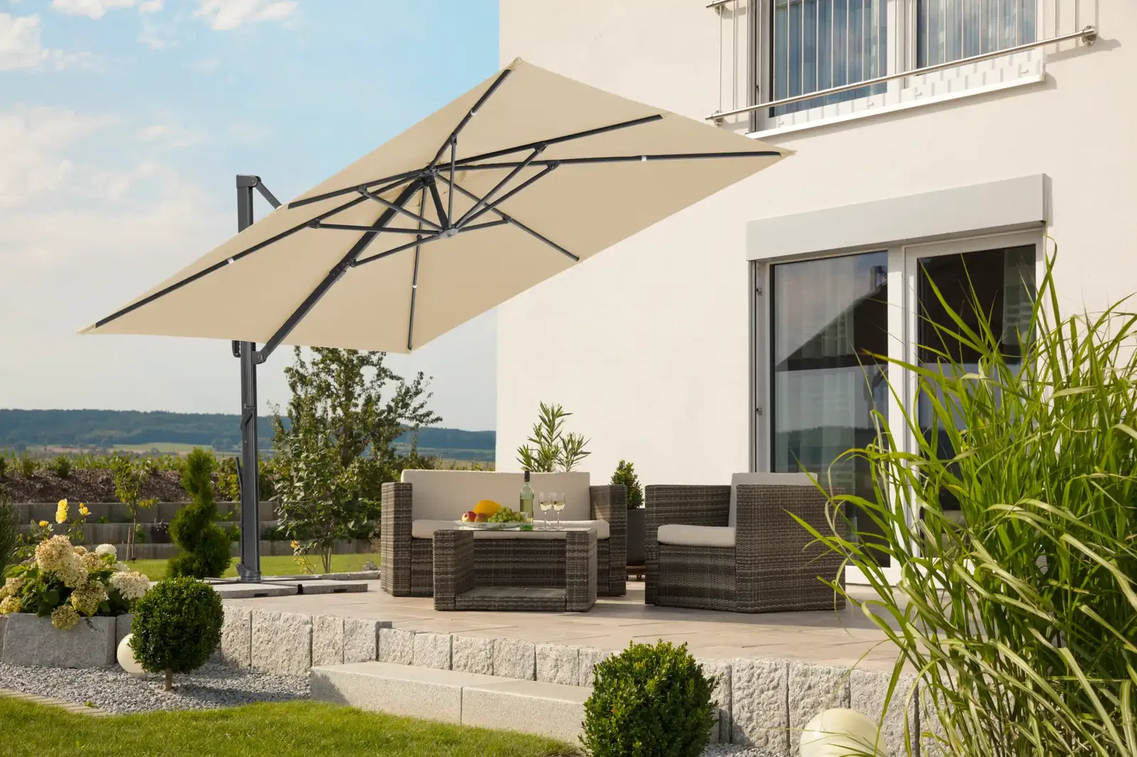 beigefarbener Sonnenschirm spendet Schatten über einer Gartenlounge