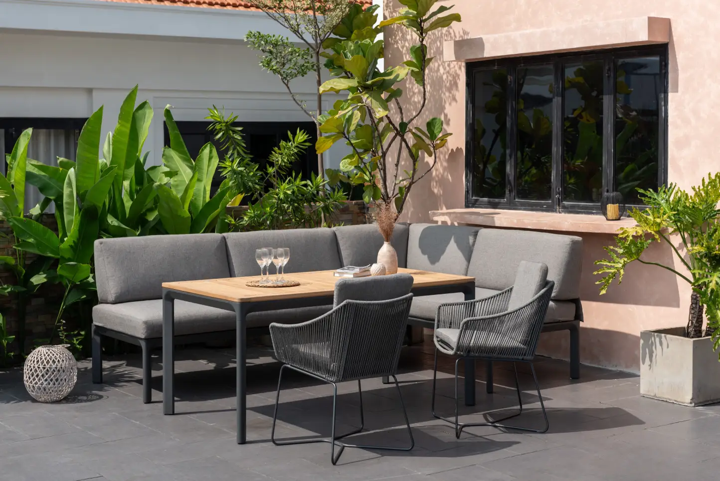 Alu-Ecklounge Dalgas mit grauem Sitzbezug in einem grün bewachsenen Innenhof.