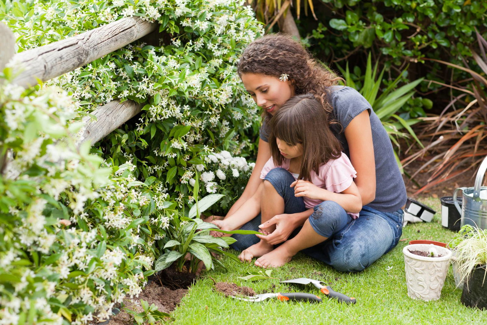 Mutter pflanzt mit Tochter im Garten eine Pflanze ein